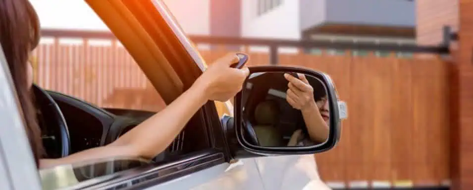 A person in a car holding a remote control towards a gate